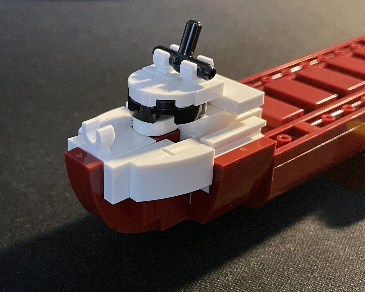 Close-up of a red and white toy boat model made from interlocking bricks on a dark surface.