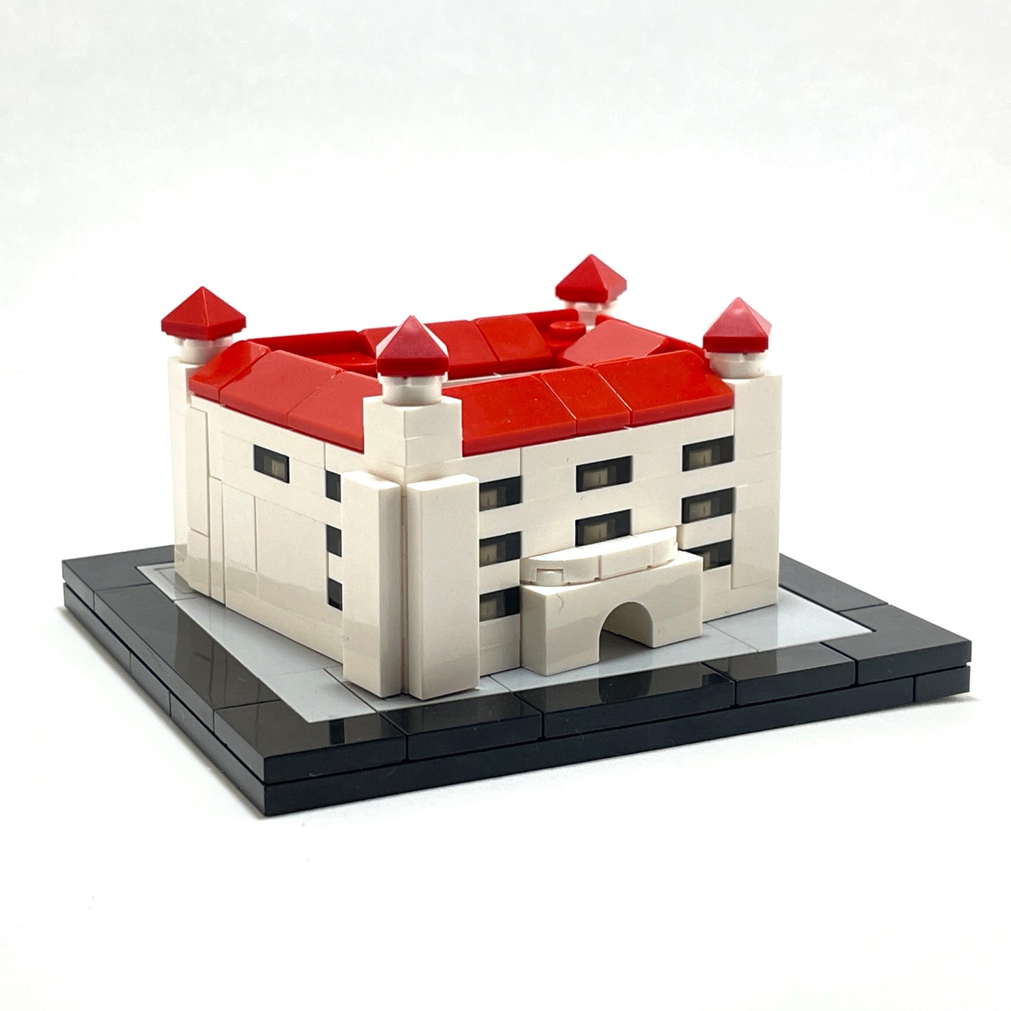Model of a castle made from interlocking bricks with red roofs on a white background.