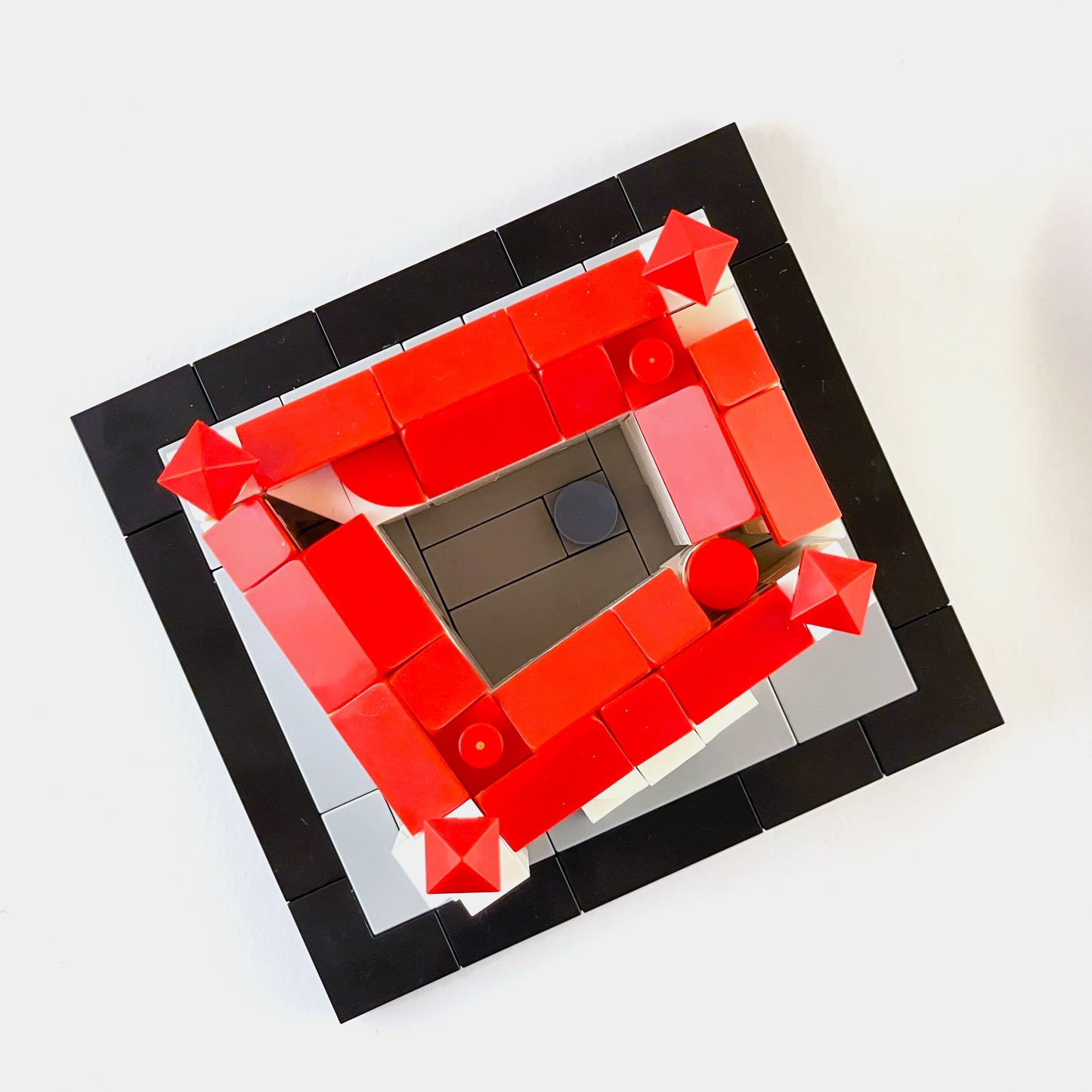 Geometric design made of red and black building blocks on a white background.