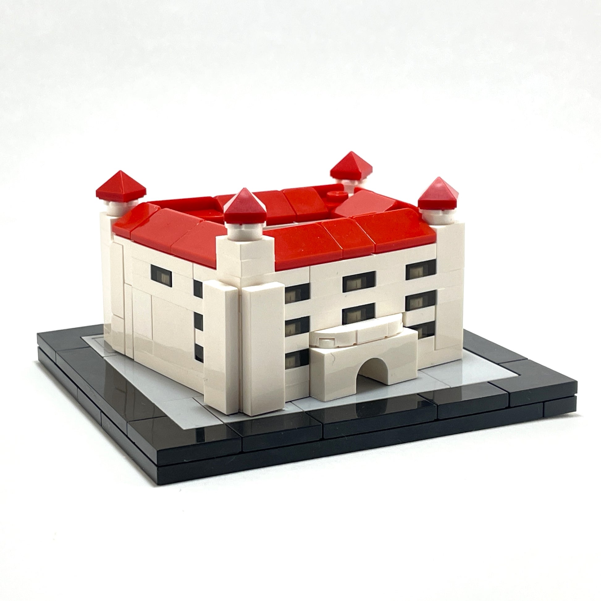 Model of a castle made from interlocking bricks with red roofs on a white background.