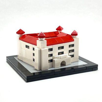 Model of a castle made from interlocking bricks with red roofs on a white background.