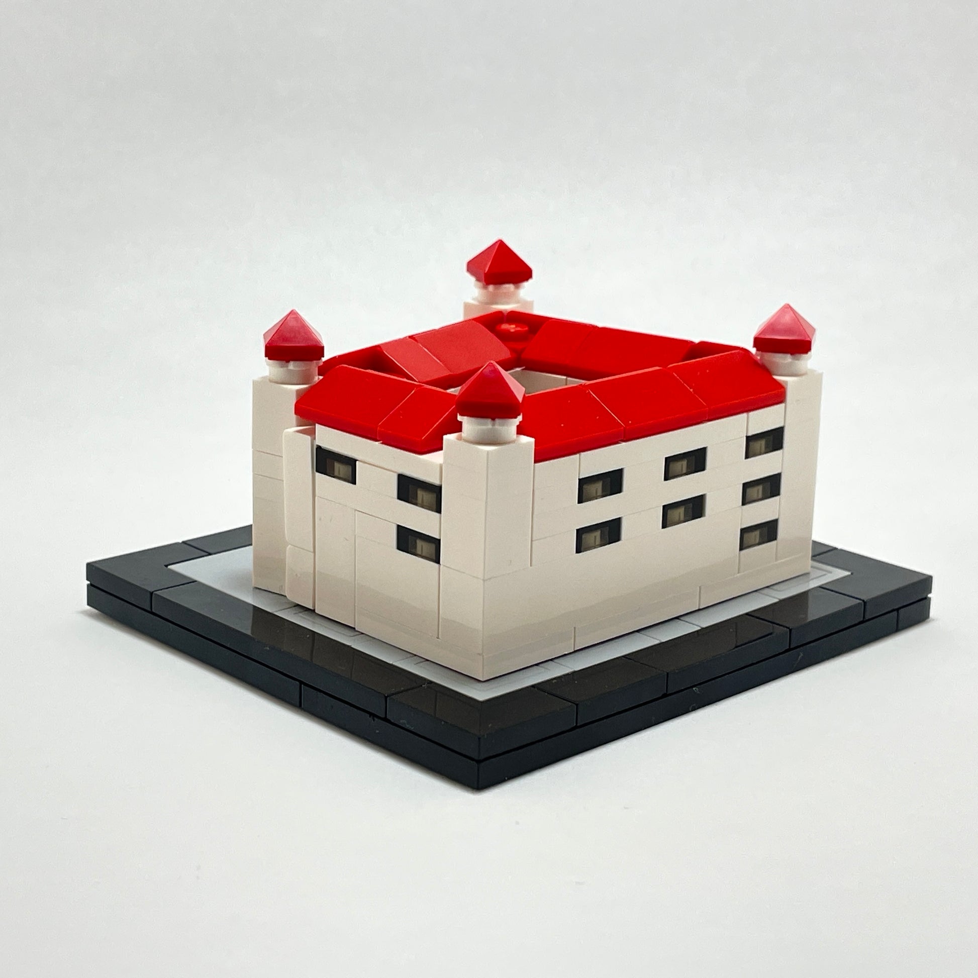Model of a castle with red roofs and white walls on a black base.